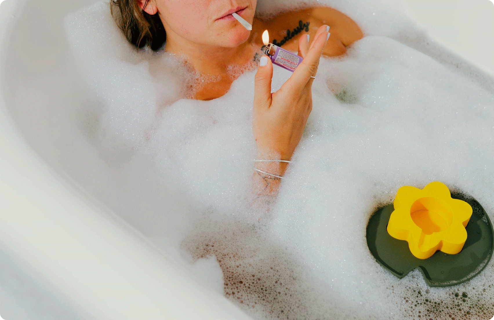 Human lighting joint with yellow Floating Ashtray in bath